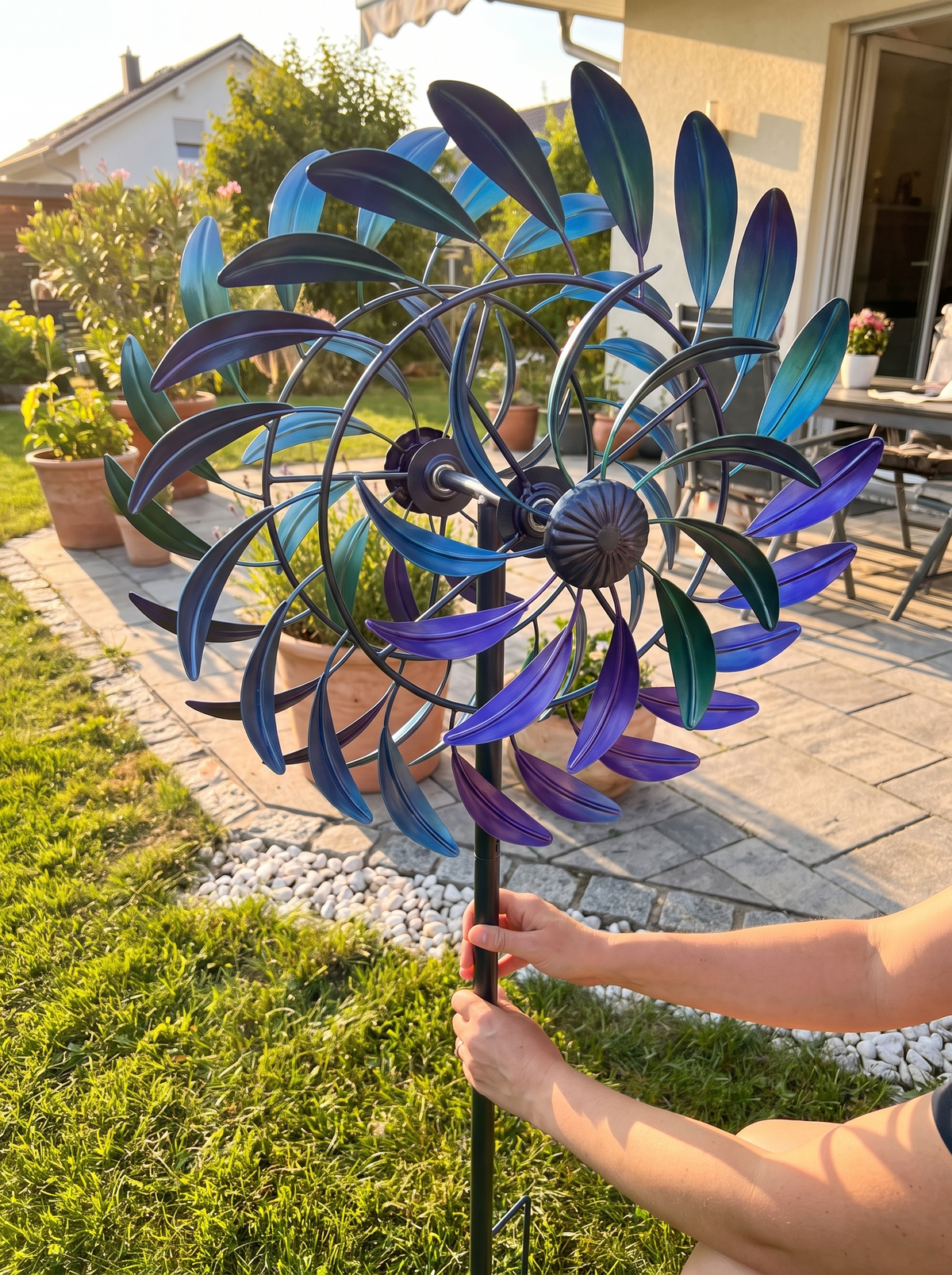 Person steckt den Windspinner in den Rasen neben der Terrasse